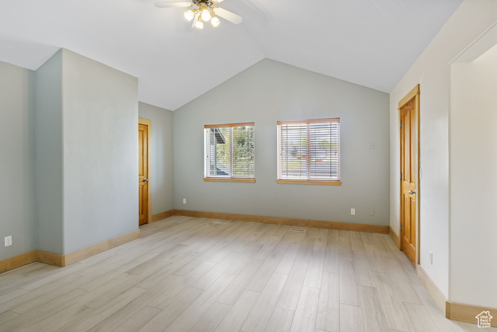 Spare room featuring a ceiling fan, baseboards, vaulted ceiling, and light wood finished floors
