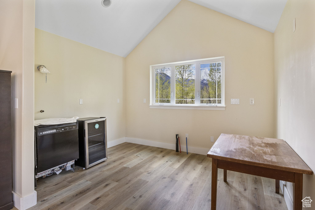 Office space featuring baseboards, wine cooler, wood finished floors, and vaulted ceiling