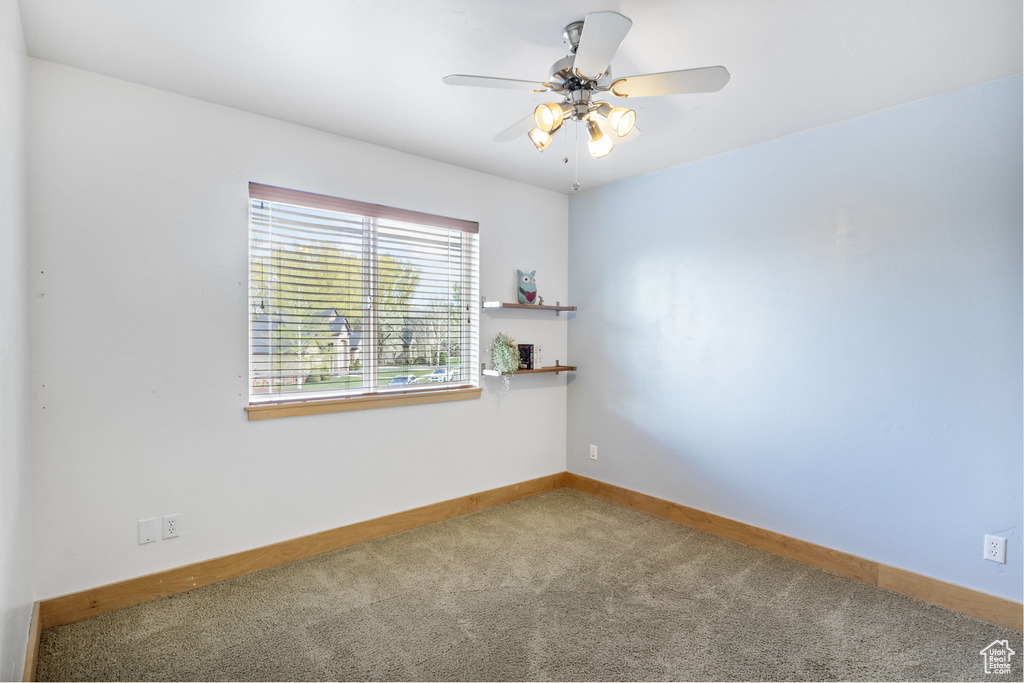 Carpeted spare room featuring baseboards and ceiling fan