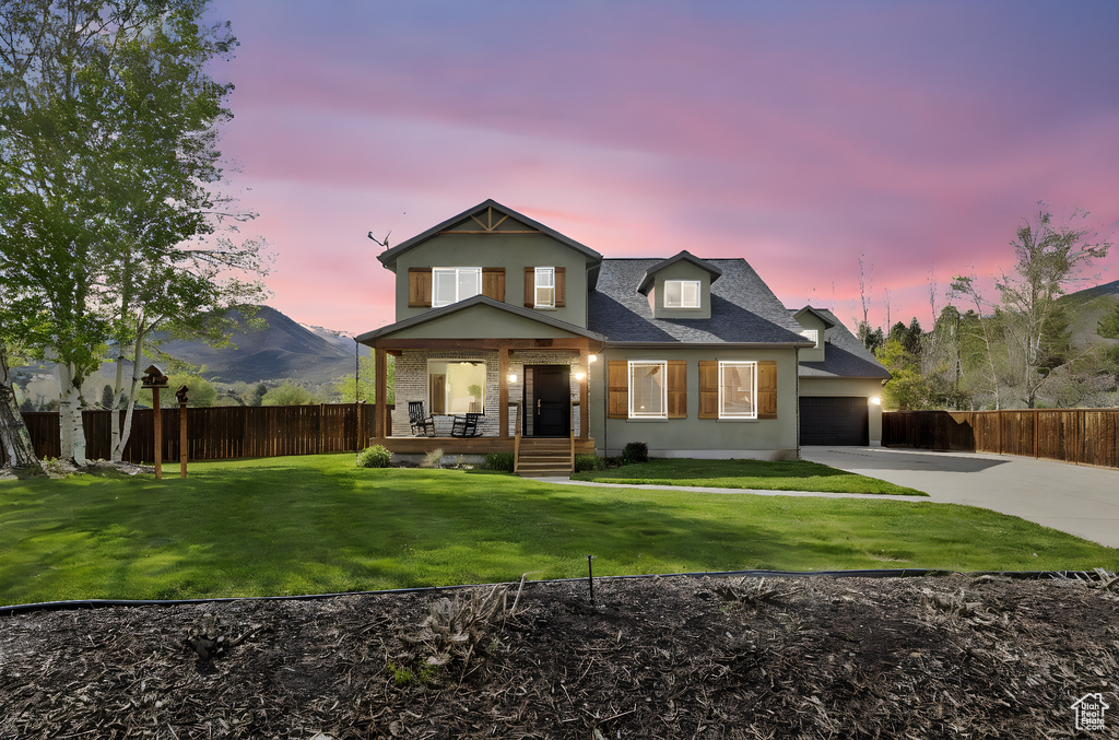 View of front of property with fence, covered porch, concrete driveway, and a front yard