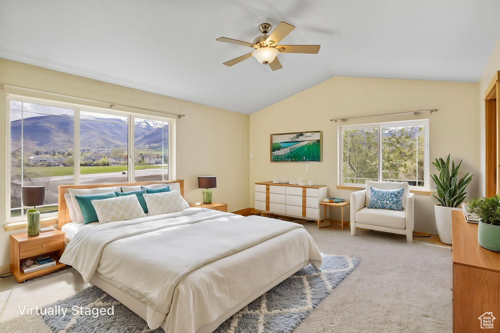 Bedroom with a ceiling fan, light carpet, and vaulted ceiling