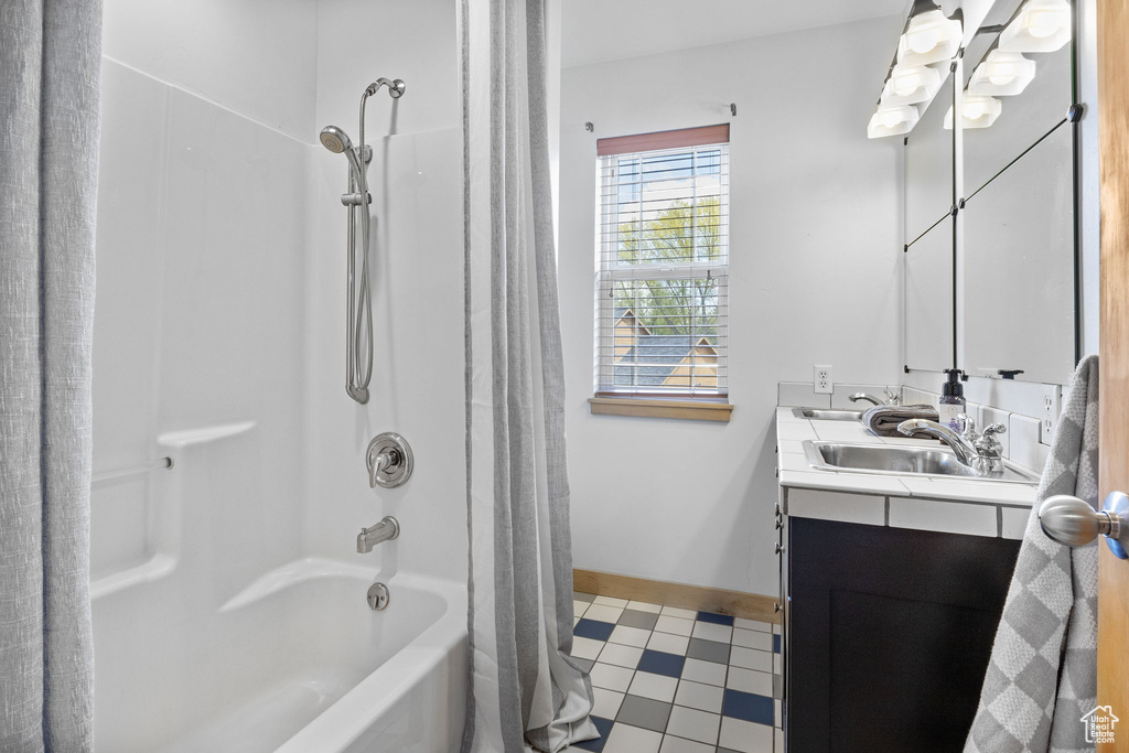 Bathroom featuring baseboards, tile patterned flooring, shower / tub combo, and vanity