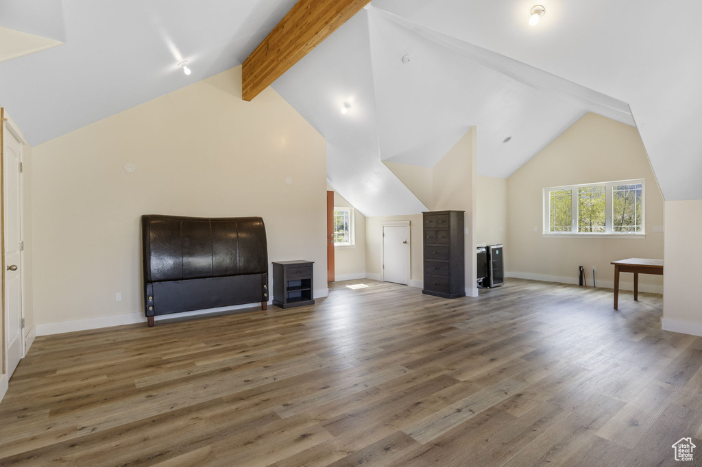 Additional living space with baseboards, lofted ceiling with beams, and wood finished floors