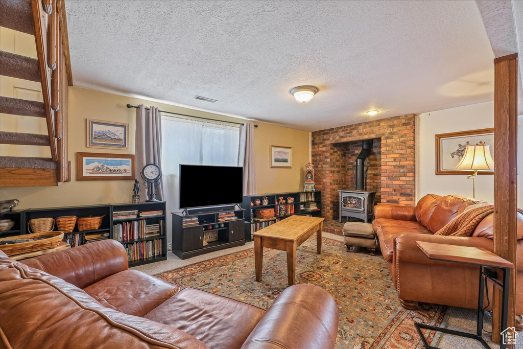Carpeted living room with a wood stove, a textured ceiling, and visible vents