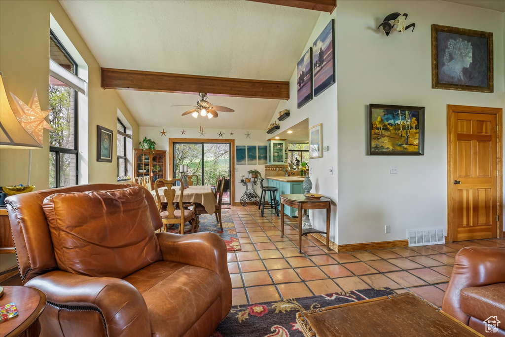 Tiled living room with visible vents, a ceiling fan, baseboards, and vaulted ceiling with beams