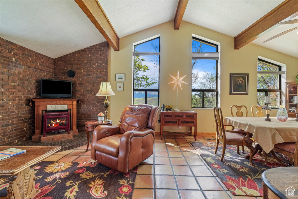 Tiled living area featuring vaulted ceiling with beams, ceiling fan, and a fireplace