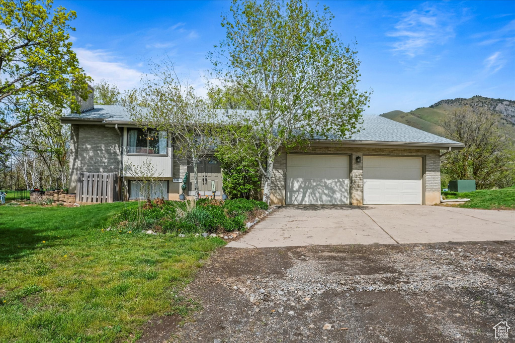View of front facade with brick siding, a mountain view, a front yard, and concrete driveway