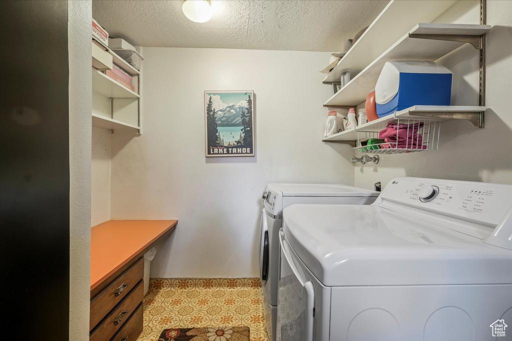 Clothes washing area featuring washing machine and clothes dryer, a textured ceiling, and laundry area