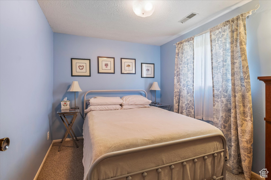 Carpeted bedroom with a textured ceiling, baseboards, and visible vents