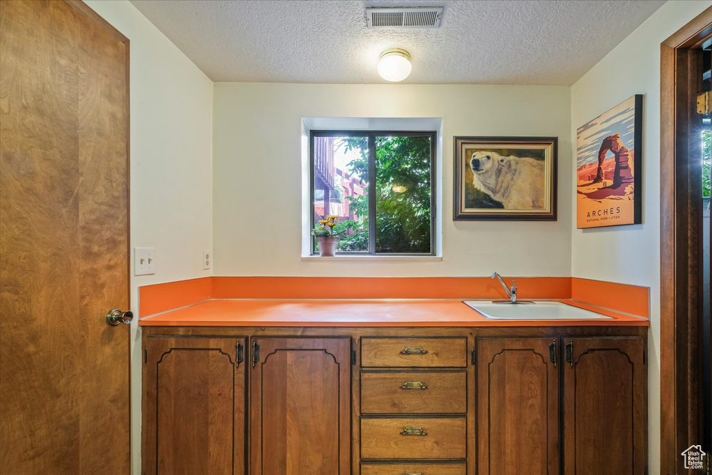 Interior space featuring visible vents, a sink, and a textured ceiling