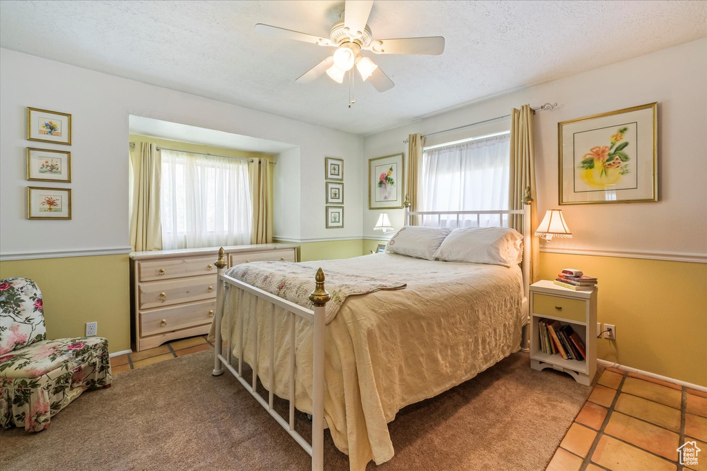 Tiled bedroom with multiple windows, a ceiling fan, and a textured ceiling