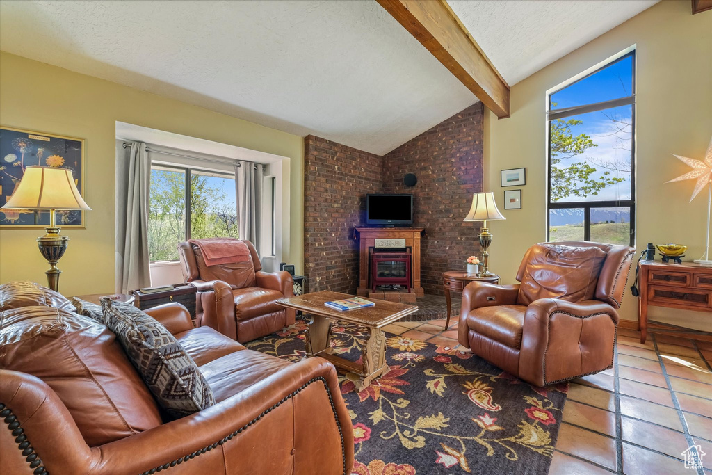 Tiled living room featuring lofted ceiling with beams, a brick fireplace, and a textured ceiling