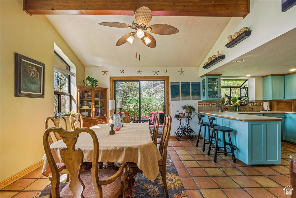 Tiled dining area with baseboards, ceiling fan, and lofted ceiling with beams