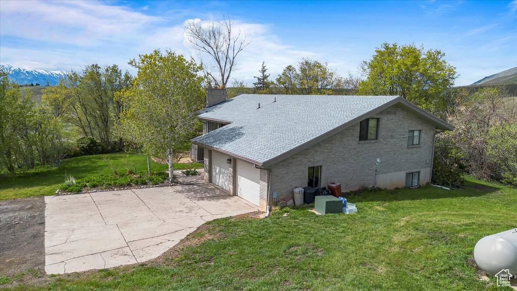 Exterior space with a yard, a chimney, concrete driveway, and brick siding