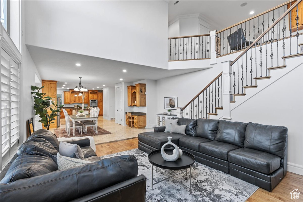 Living room featuring recessed lighting, a towering ceiling, a notable chandelier, and stairway