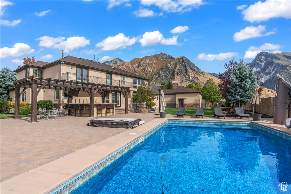 View of pool with outdoor dry bar, a patio, a fenced in pool, a mountain view, and a pergola