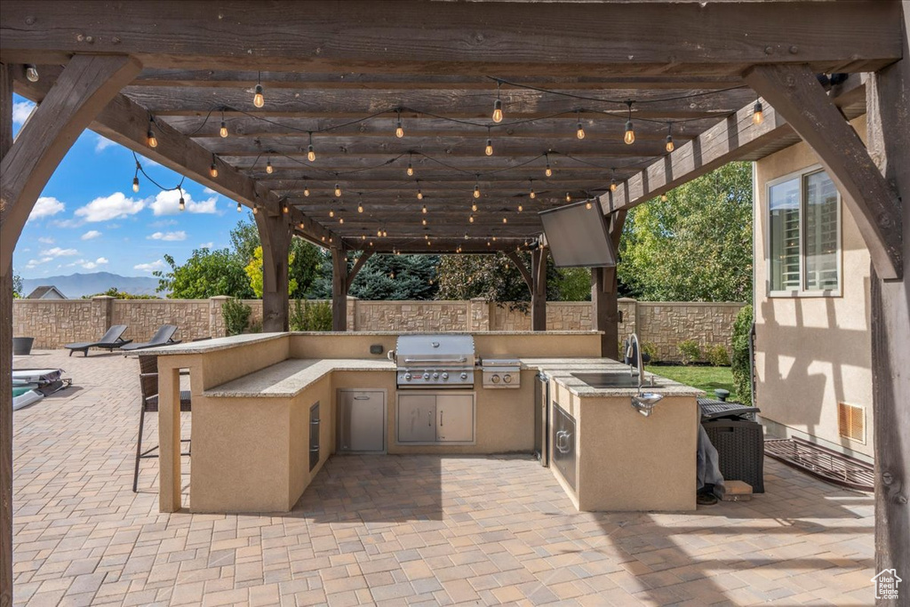 View of patio / terrace featuring a sink, an outdoor kitchen, a fenced backyard, and a grill