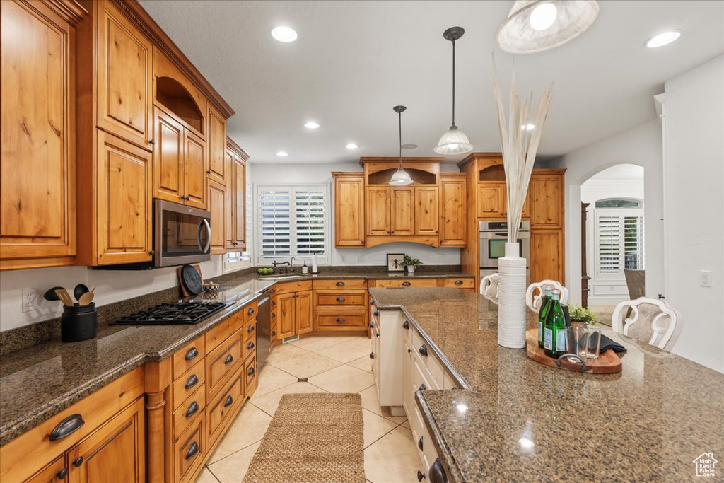Kitchen with arched walkways, appliances with stainless steel finishes, a healthy amount of sunlight, and recessed lighting