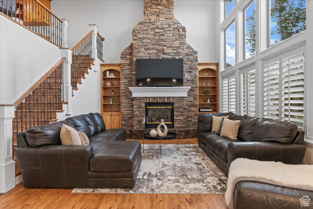 Living room featuring stairs, a fireplace, wood finished floors, and a towering ceiling