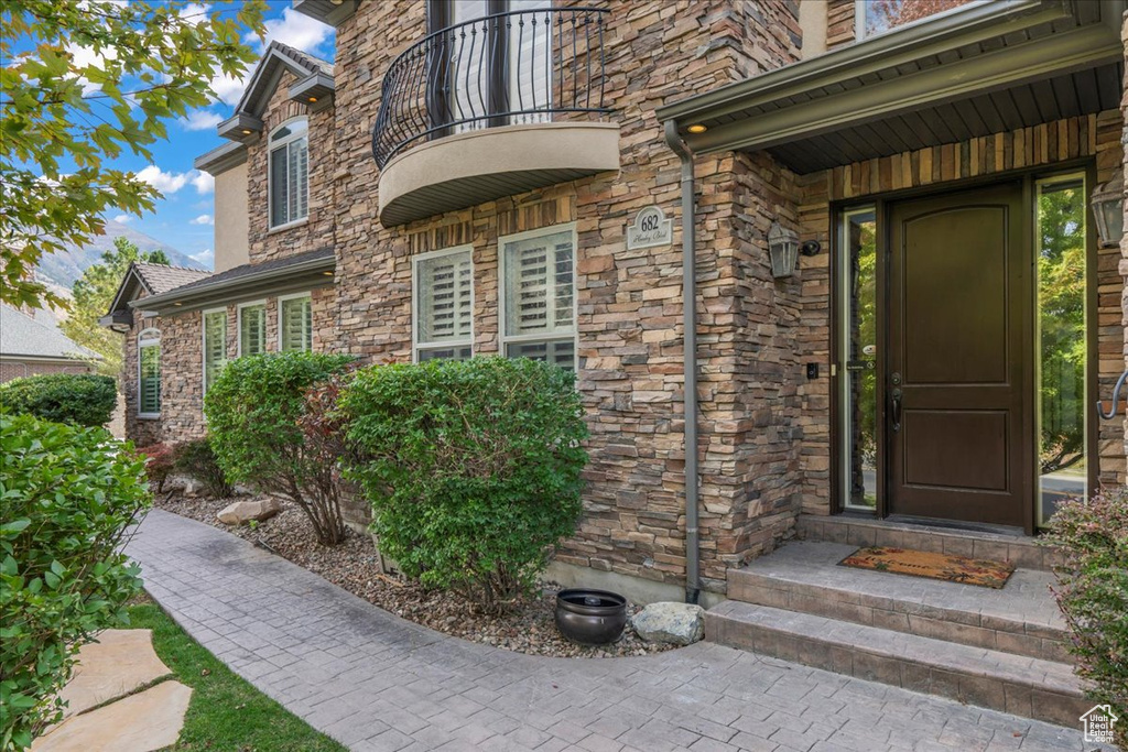 Doorway to property featuring a balcony and stone siding