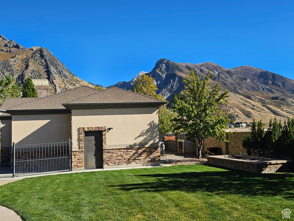 View of front of home with fence, a mountain view, stucco siding, and a front lawn