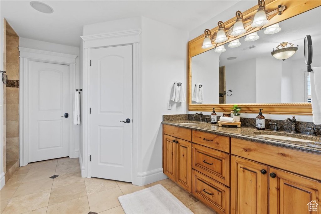 Full bathroom featuring double vanity, a sink, baseboards, and tile patterned flooring