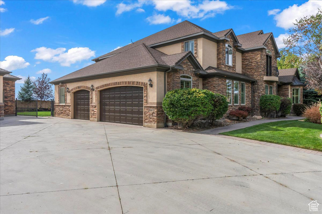 View of property exterior with a garage, fence, stone siding, stucco siding, and driveway