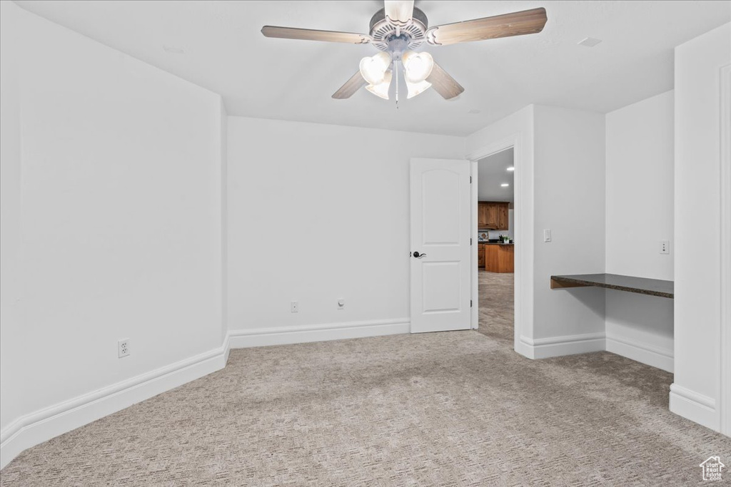 Spare room featuring carpet floors, a ceiling fan, and baseboards