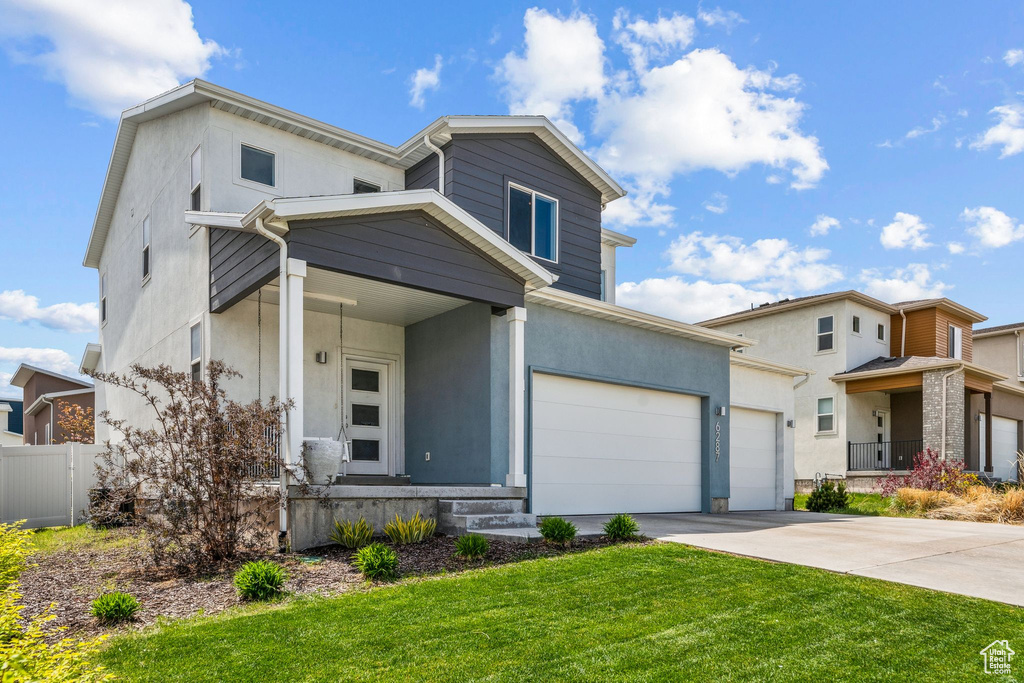 View of front facade with stucco siding, fence, a front yard, and concrete driveway