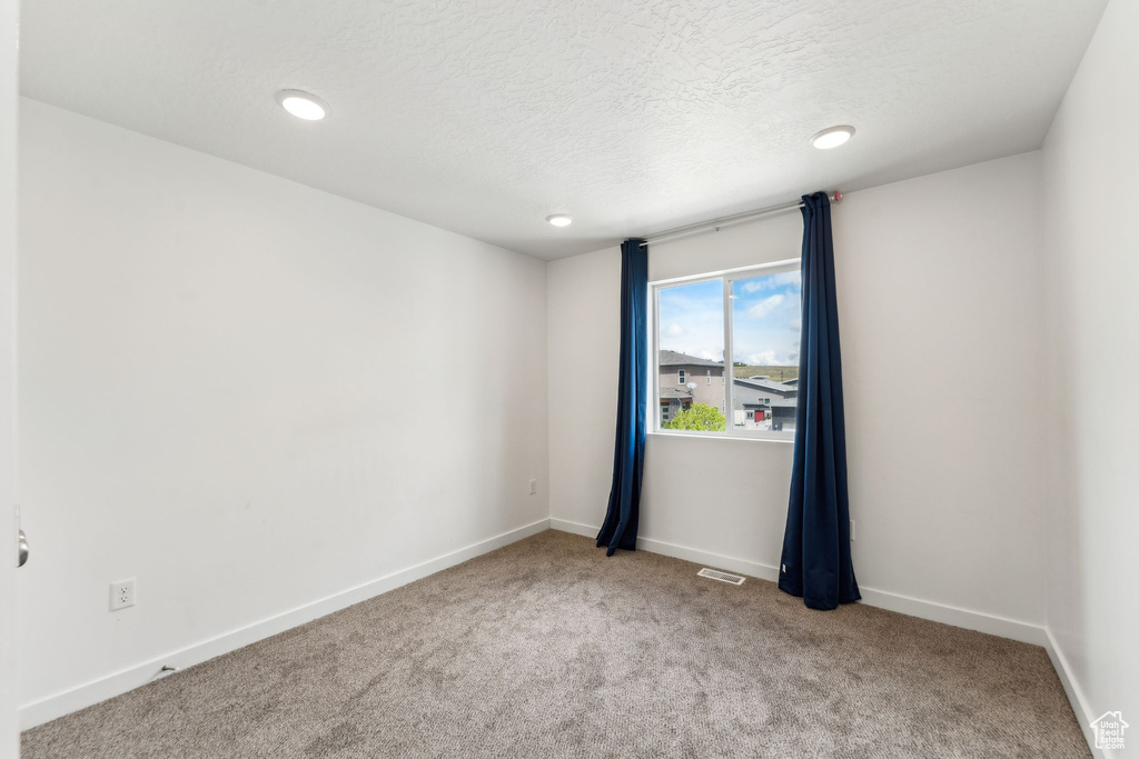 Spare room featuring visible vents, a textured ceiling, carpet, and recessed lighting