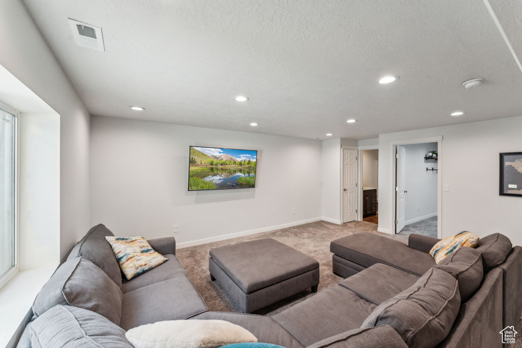 Living area with a textured ceiling, visible vents, baseboards, light carpet, and recessed lighting