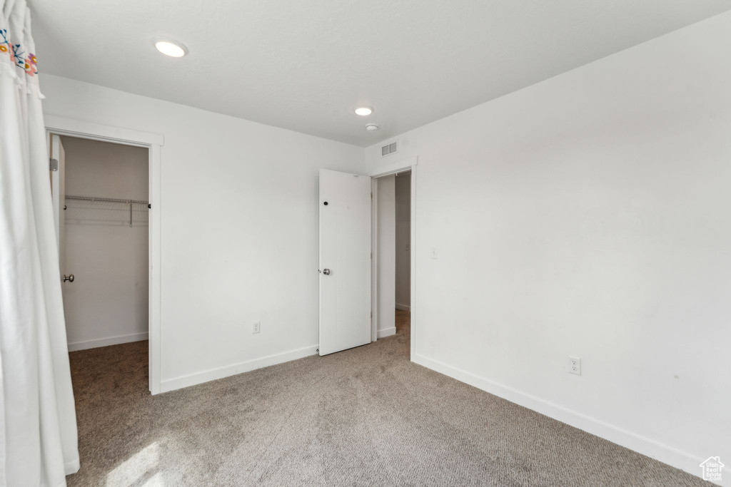 Unfurnished bedroom featuring carpet, recessed lighting, baseboards, a spacious closet, and visible vents