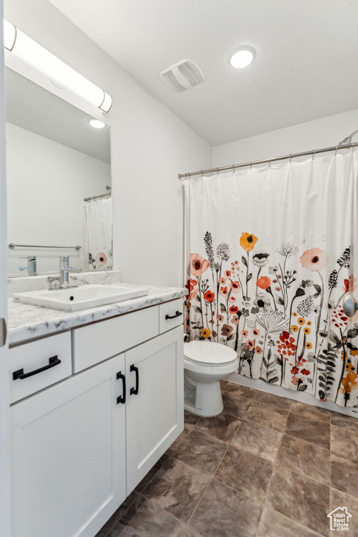 Bathroom with toilet, visible vents, and vanity