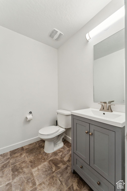 Half bathroom with visible vents, baseboards, toilet, and vanity
