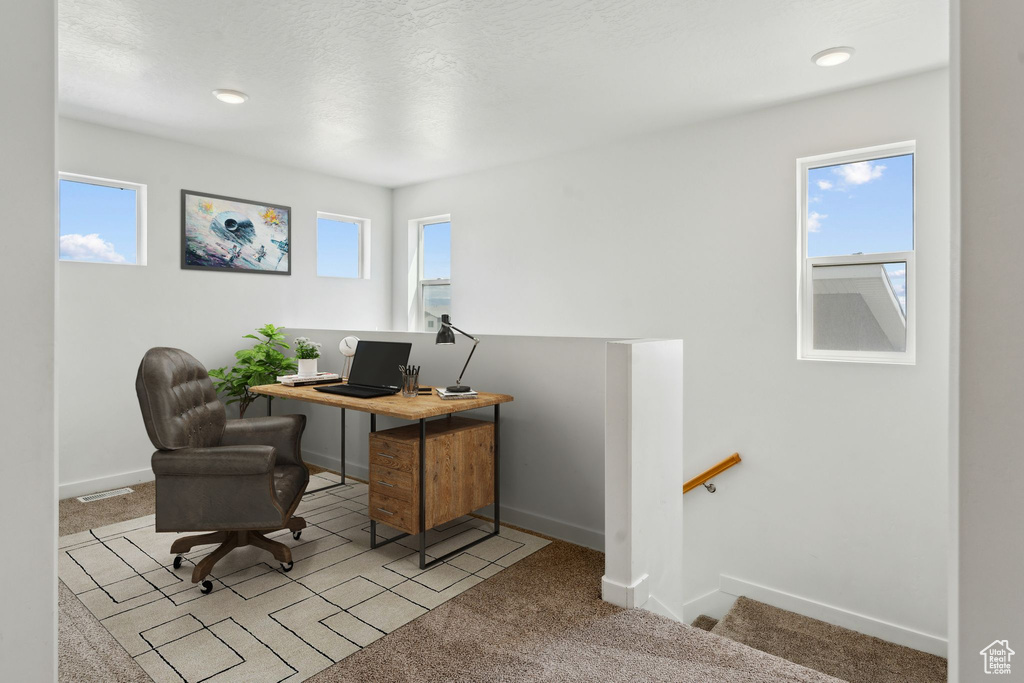 Carpeted office with plenty of natural light and baseboards