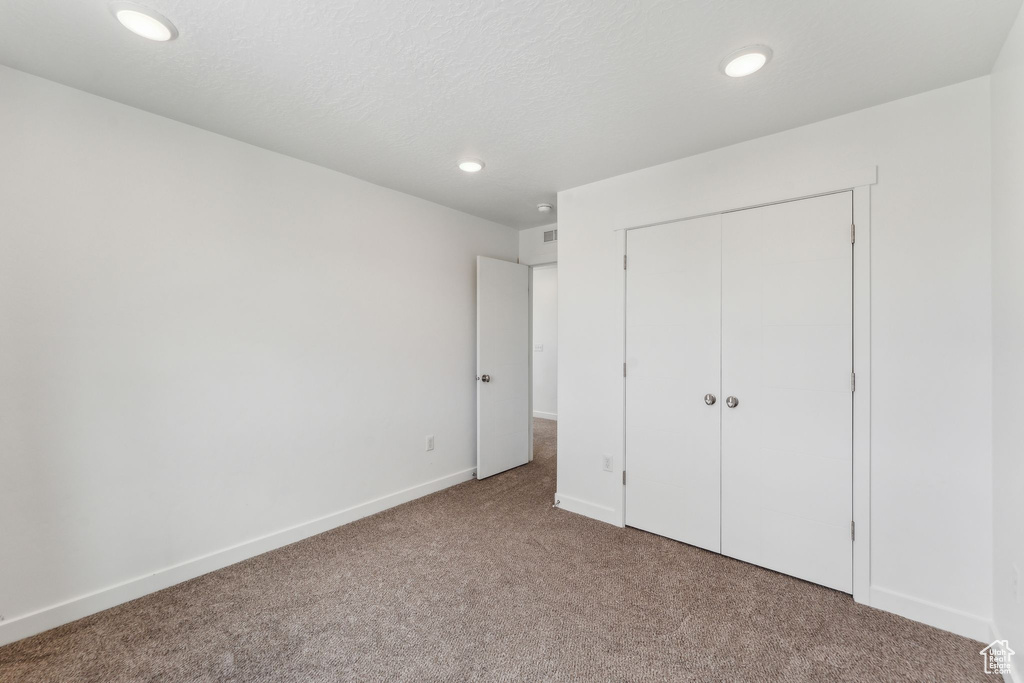 Unfurnished bedroom featuring carpet floors, recessed lighting, baseboards, and a closet