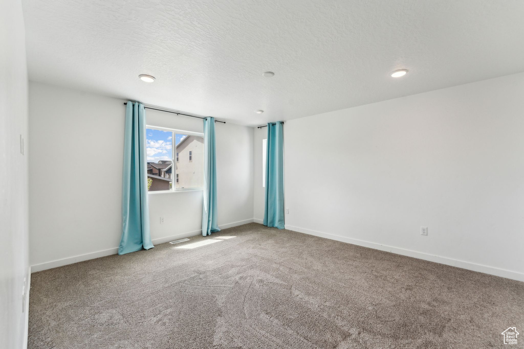 Spare room with baseboards, a textured ceiling, and carpet