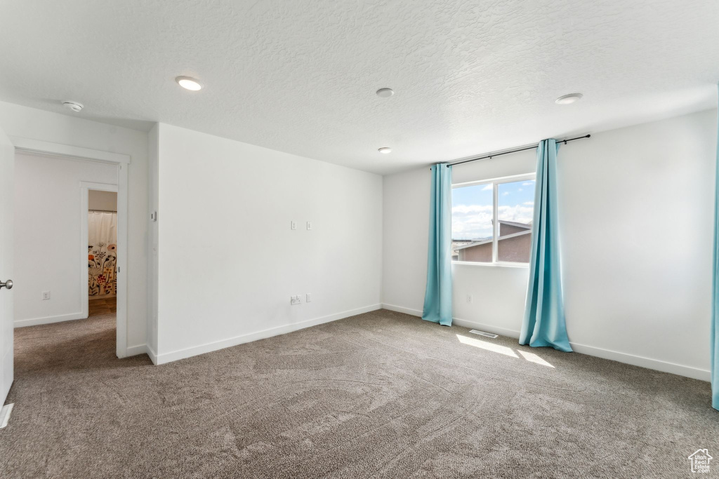 Spare room with a textured ceiling, carpet, recessed lighting, baseboards, and visible vents