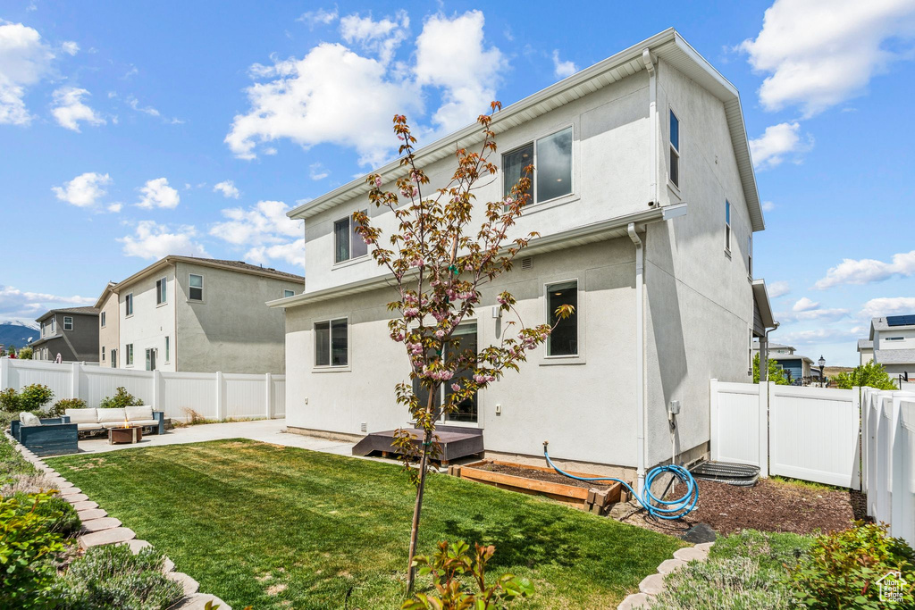 Back of property featuring a yard, a patio, an outdoor hangout area, and a fenced backyard