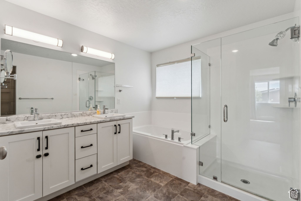 Full bathroom featuring double vanity, a shower stall, a sink, and a bath