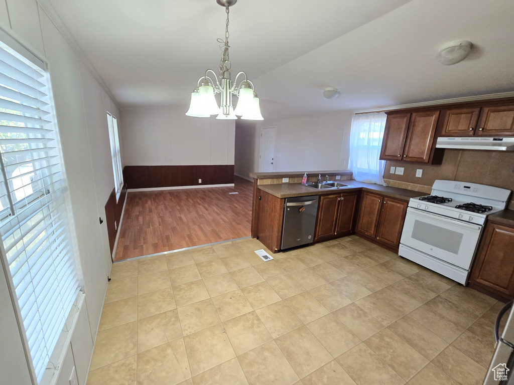 Kitchen with stainless steel dishwasher, an inviting chandelier, a sink, dark countertops, and white gas range oven