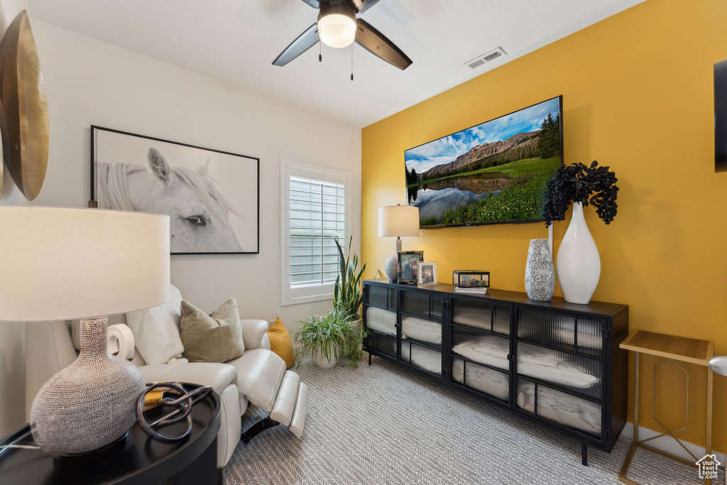 Living area featuring visible vents, carpet flooring, and a ceiling fan