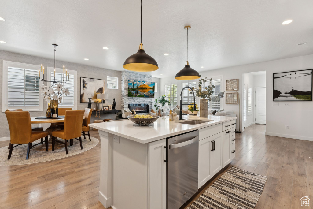 Kitchen featuring white cabinets, a sink, a fireplace, open floor plan, and stainless steel dishwasher
