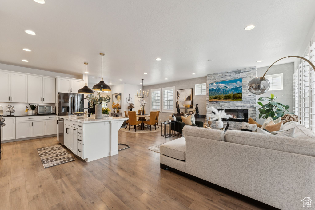 Living room featuring recessed lighting, light wood-style flooring, and a fireplace