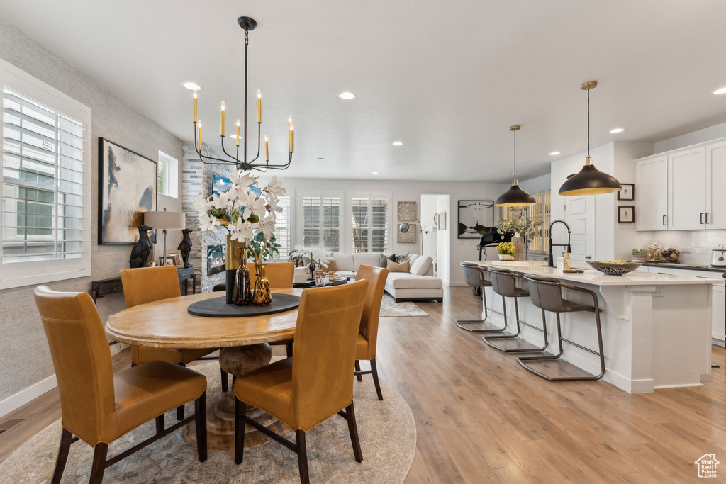 Dining room with recessed lighting, baseboards, an inviting chandelier, and light wood-type flooring