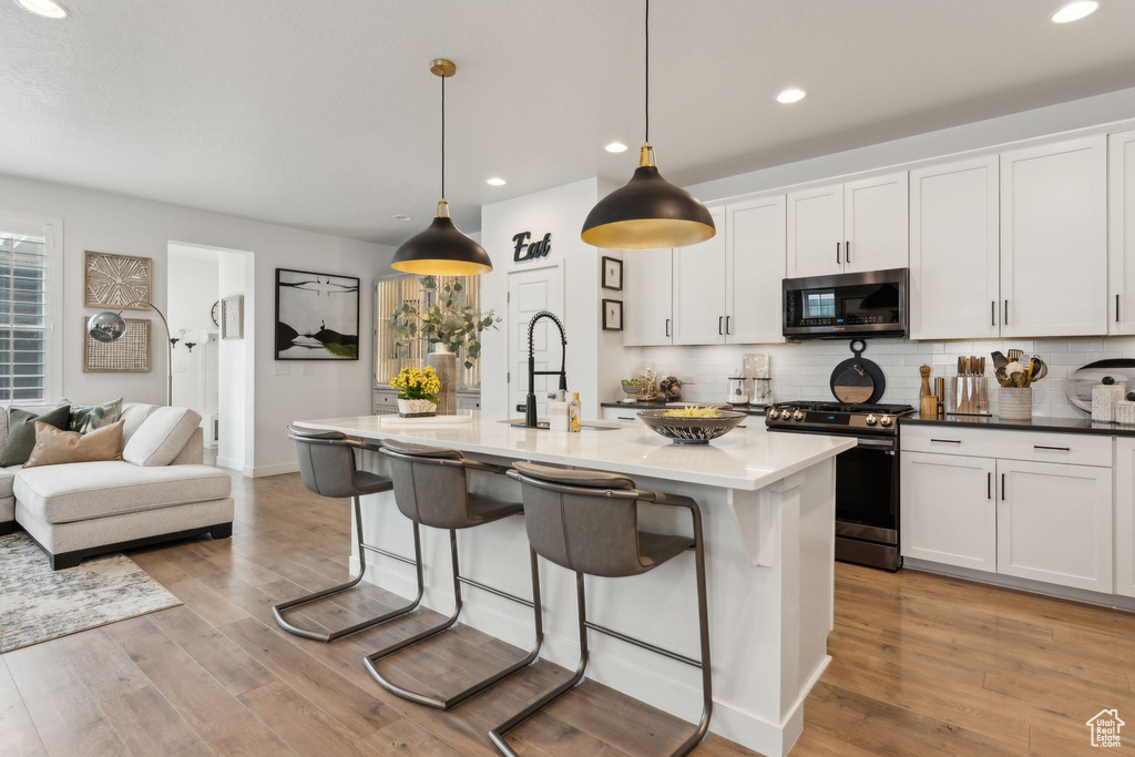 Kitchen featuring a kitchen breakfast bar, recessed lighting, stainless steel range with gas stovetop, a sink, and backsplash