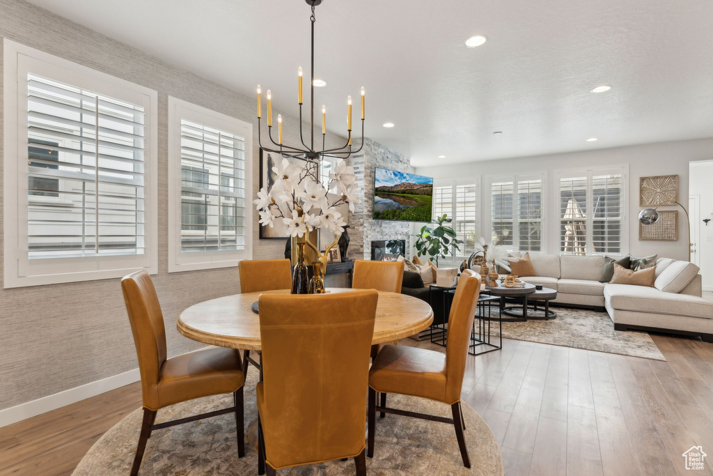 Dining area with a fireplace, a chandelier, recessed lighting, baseboards, and wood finished floors