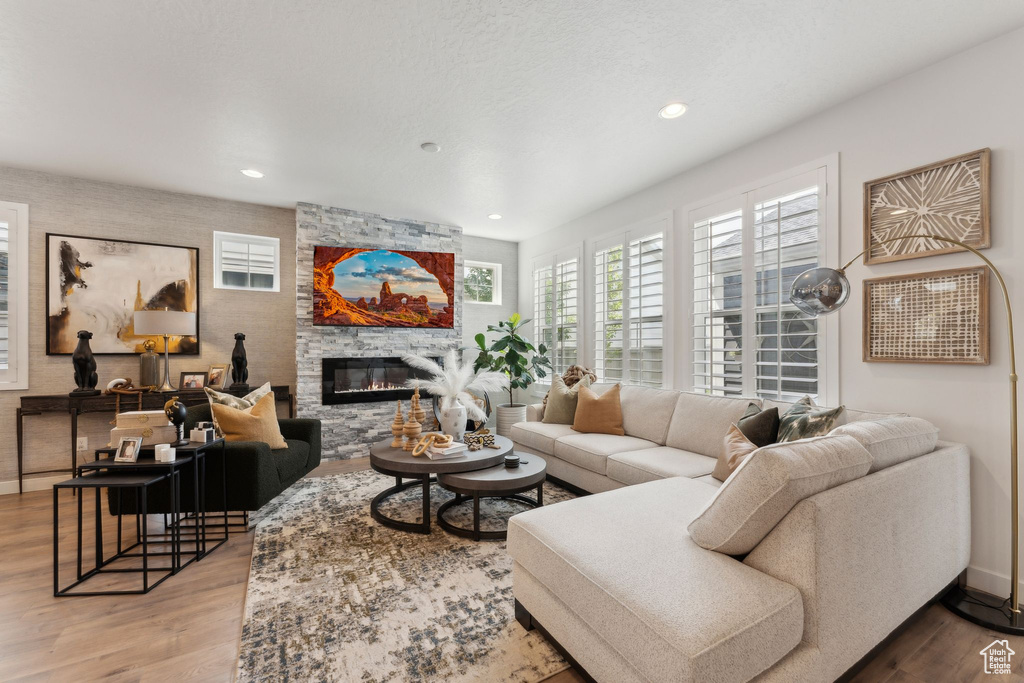 Living room with a stone fireplace, recessed lighting, and wood finished floors