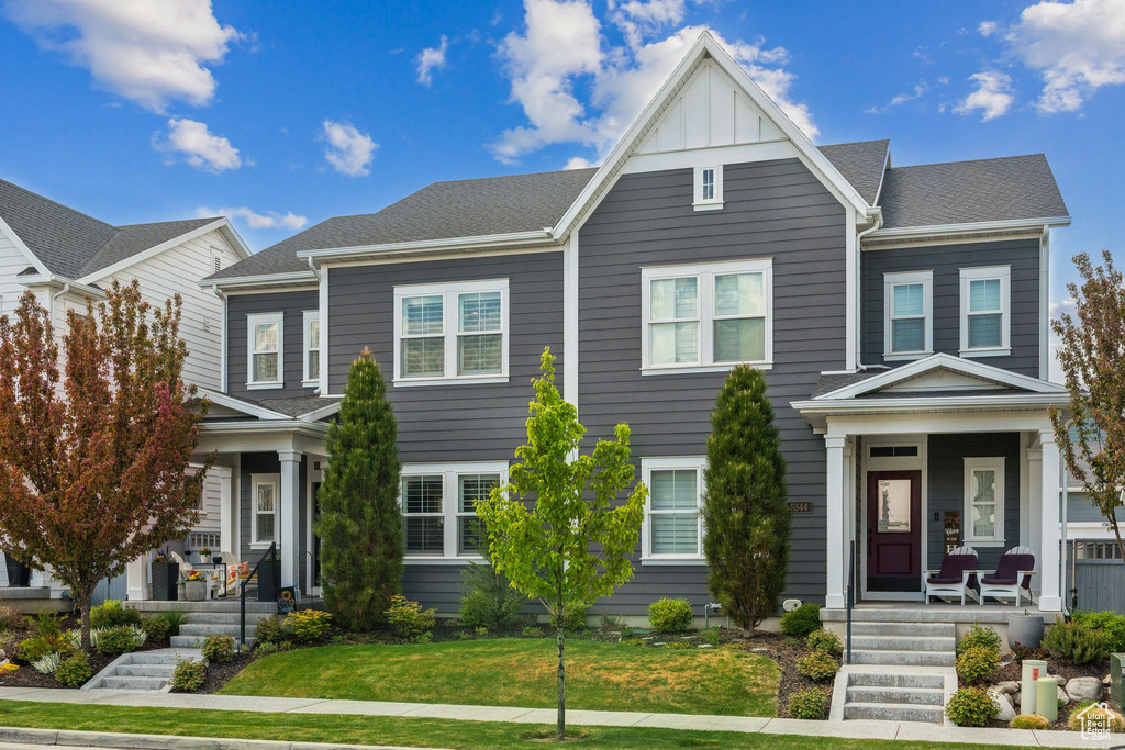 Townhome / multi-family property with board and batten siding, a porch, and a front yard