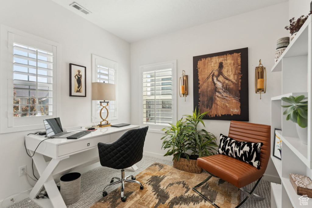 Office space featuring baseboards, visible vents, and plenty of natural light